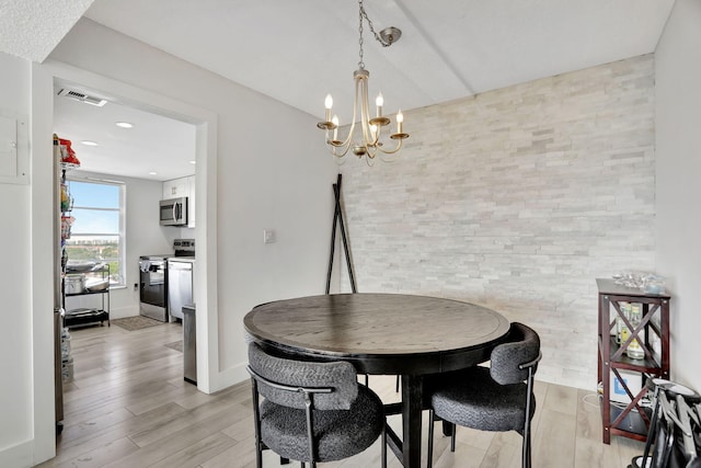 dining space with light wood-type flooring and a notable chandelier