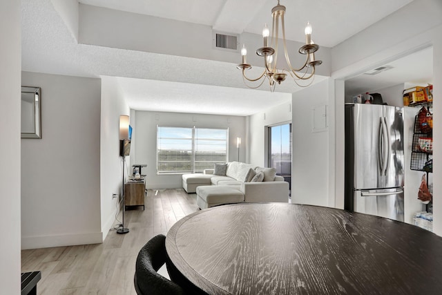 dining space featuring a notable chandelier, a textured ceiling, and light hardwood / wood-style flooring