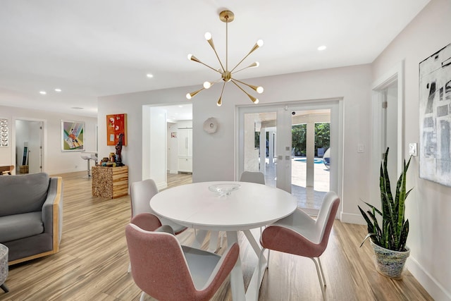 dining space featuring an inviting chandelier, light wood-type flooring, and french doors