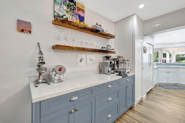 bar featuring light wood-type flooring and white cabinetry