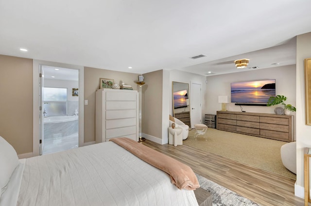 bedroom with hardwood / wood-style flooring and ensuite bath