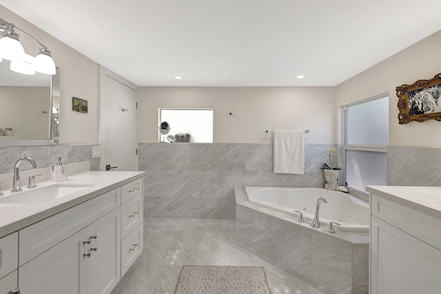 bathroom featuring a relaxing tiled tub, plenty of natural light, and vanity