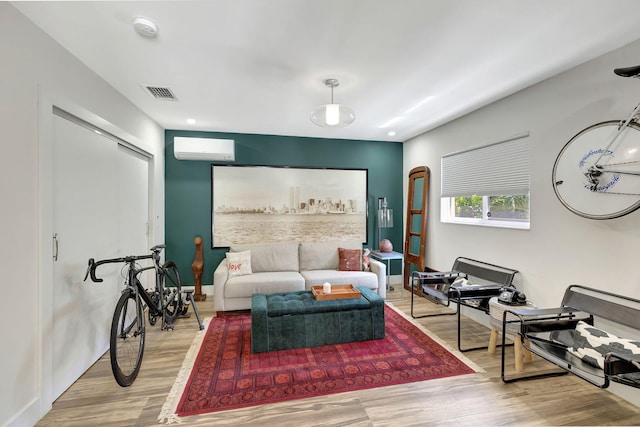 living room with a wall unit AC and light hardwood / wood-style floors