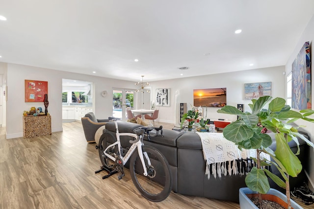 living room featuring light wood-type flooring, a chandelier, and french doors