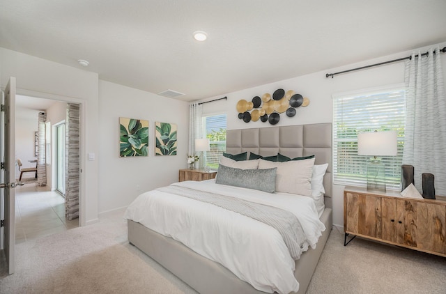 bedroom featuring light carpet, light tile patterned floors, baseboards, and visible vents