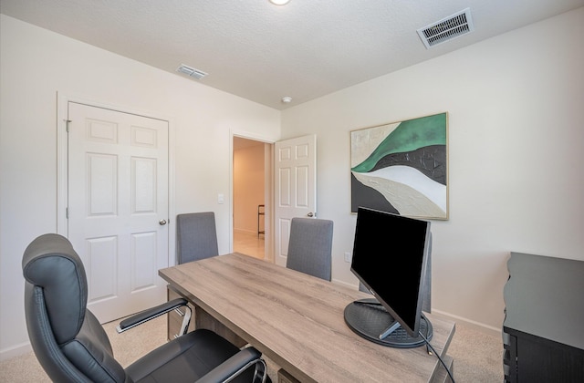 carpeted office with visible vents, a textured ceiling, and baseboards