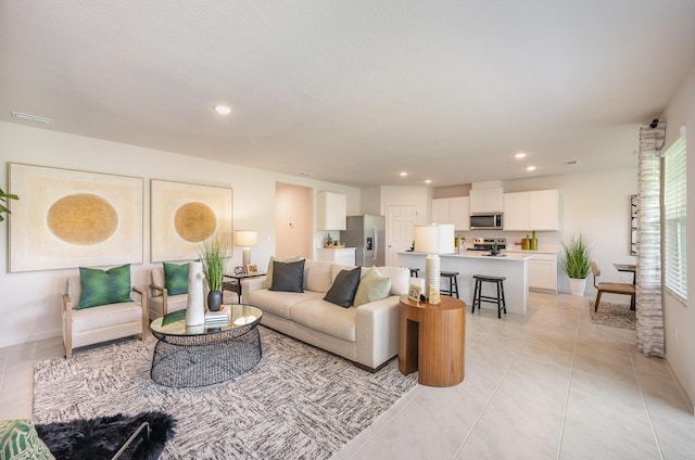 living area featuring light tile patterned floors, visible vents, recessed lighting, and baseboards