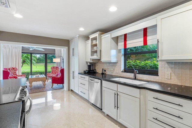 kitchen with stove, backsplash, stainless steel dishwasher, sink, and white cabinetry