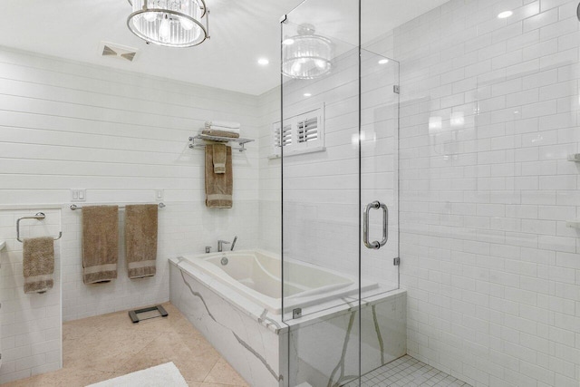 bathroom with tile patterned flooring, tile walls, independent shower and bath, and a chandelier