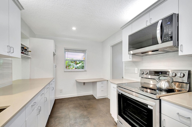 kitchen with white cabinetry, dark tile patterned floors, a textured ceiling, and appliances with stainless steel finishes