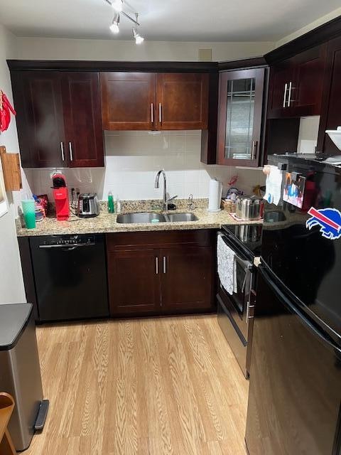 kitchen with light stone counters, tasteful backsplash, sink, light hardwood / wood-style flooring, and black appliances