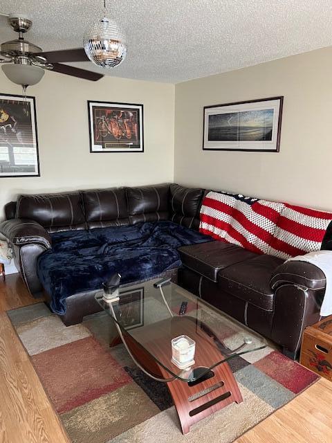 living room with a textured ceiling, hardwood / wood-style floors, and ceiling fan