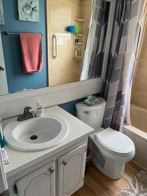 full bathroom featuring hardwood / wood-style floors, vanity, toilet, and shower / bath combo with shower curtain