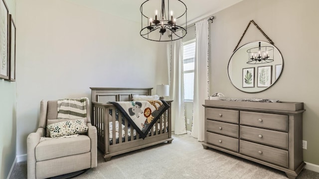 carpeted bedroom featuring a chandelier and a nursery area