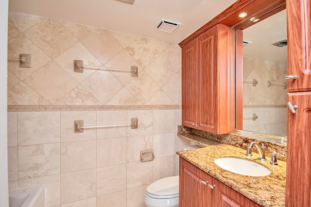 bathroom with vanity, a bathtub, toilet, and tile walls