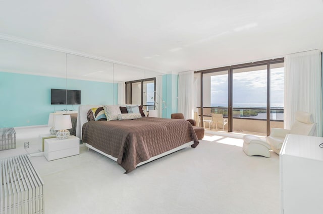 bedroom featuring ornamental molding, floor to ceiling windows, and light carpet