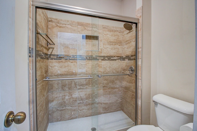 bathroom featuring toilet and a shower with shower door