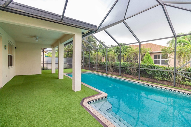 view of swimming pool with ceiling fan, a lanai, and a yard