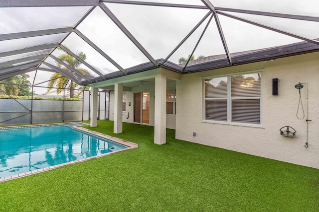 view of swimming pool featuring ceiling fan, a lanai, and a lawn