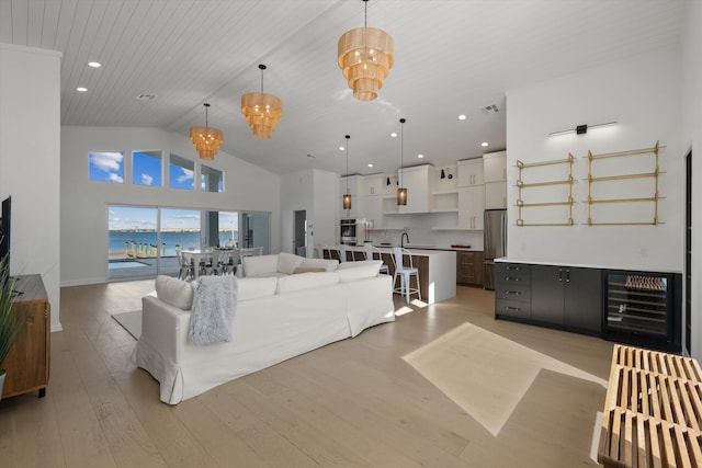 living room featuring light hardwood / wood-style floors, a water view, wine cooler, high vaulted ceiling, and wooden ceiling