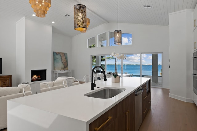 kitchen with a water view, pendant lighting, a center island with sink, hardwood / wood-style floors, and sink