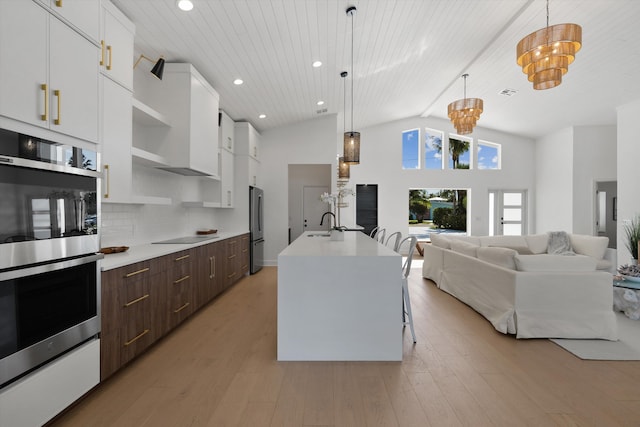 kitchen featuring dark brown cabinets, pendant lighting, white cabinetry, a center island with sink, and appliances with stainless steel finishes