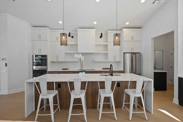 kitchen featuring an island with sink, white cabinets, appliances with stainless steel finishes, and light wood-type flooring