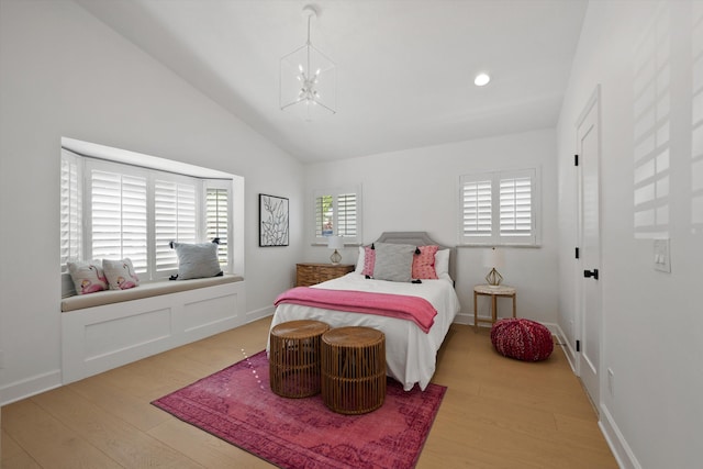 bedroom with a notable chandelier, lofted ceiling, light hardwood / wood-style floors, and multiple windows