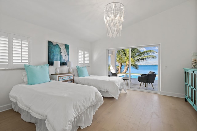 bedroom featuring light wood-type flooring, lofted ceiling, an inviting chandelier, and access to exterior