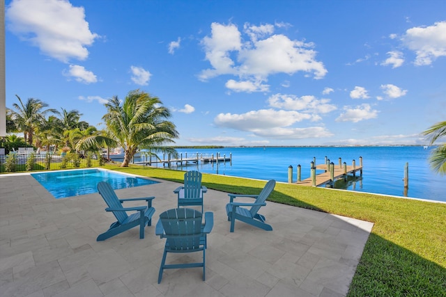 view of pool with a patio, a water view, a dock, and a yard