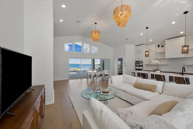 living room featuring wood ceiling, high vaulted ceiling, an inviting chandelier, light hardwood / wood-style floors, and a water view