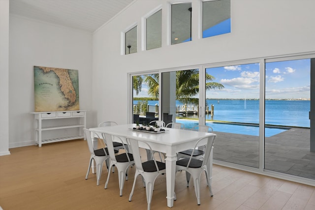 dining area with a water view, ornamental molding, and light hardwood / wood-style flooring