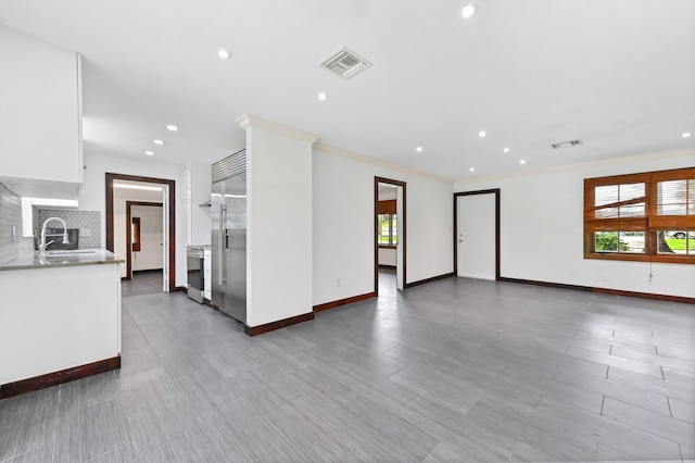 unfurnished living room with ornamental molding and sink