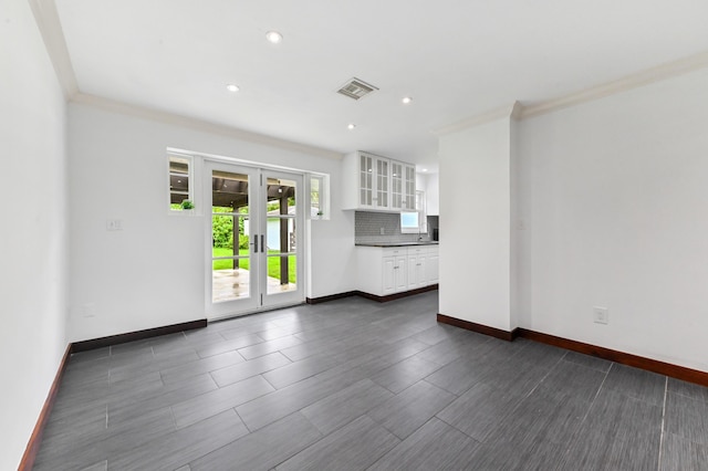 unfurnished living room with crown molding, french doors, and dark wood-type flooring