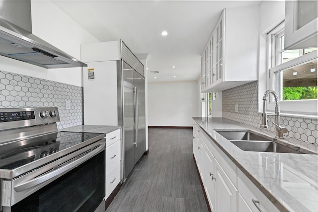 kitchen with sink, tasteful backsplash, extractor fan, white cabinets, and appliances with stainless steel finishes