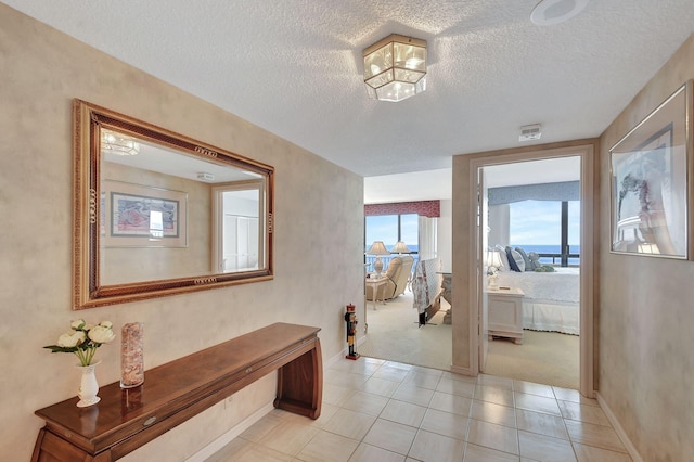 4000 N Ocean Dr Unit 2401, Singer Island, FL 33404 - corridor featuring a textured ceiling, light carpet, baseboards, and light tile patterned floors