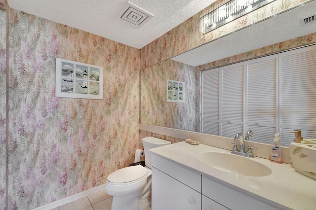 bathroom featuring tile patterned flooring, a textured ceiling, vanity, and toilet