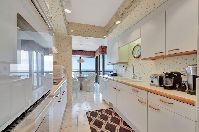 kitchen featuring hanging light fixtures, white cabinets, white appliances, light tile patterned floors, and sink