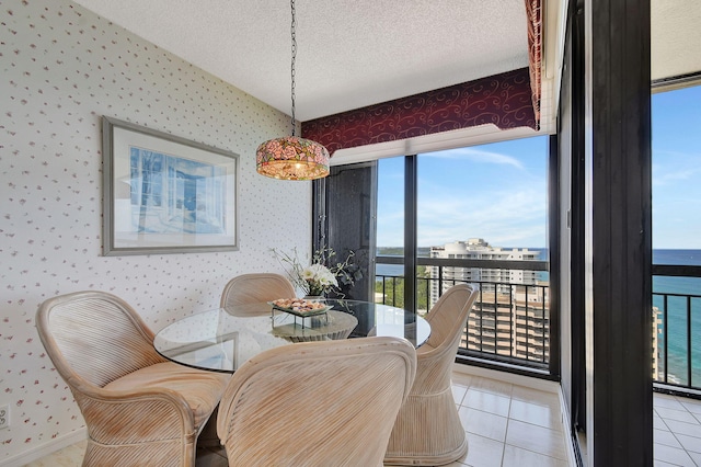 tiled dining space featuring a textured ceiling, plenty of natural light, and a water view