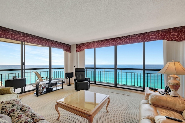 carpeted living room featuring a textured ceiling, a water view, and a wealth of natural light