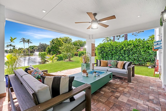 view of patio / terrace with an outdoor living space, a water view, and ceiling fan