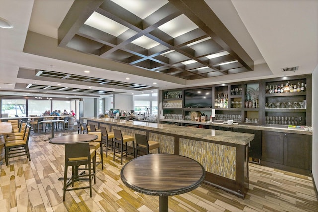 bar featuring light hardwood / wood-style floors, coffered ceiling, and a healthy amount of sunlight