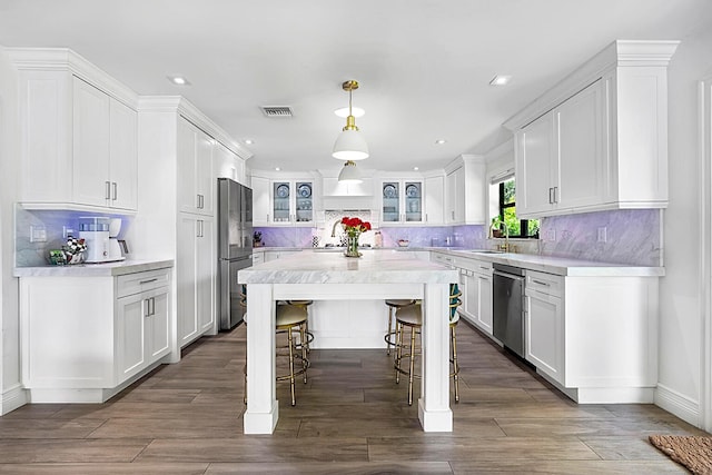 kitchen featuring pendant lighting, a kitchen bar, stainless steel appliances, and white cabinets