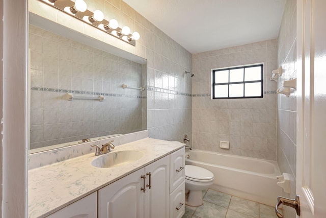 full bathroom with tile walls, tile patterned flooring, tiled shower / bath combo, vanity, and toilet