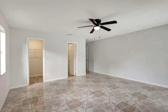 unfurnished bedroom featuring ceiling fan, a closet, and a spacious closet