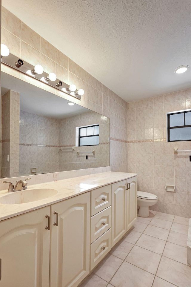 bathroom with vanity, tile walls, tile patterned flooring, and toilet