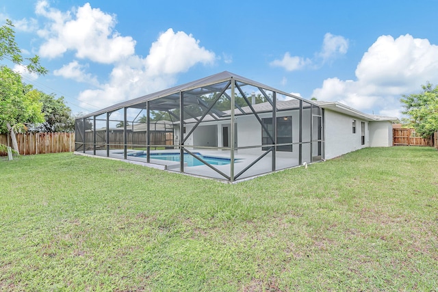 rear view of property with a yard, a fenced in pool, glass enclosure, and a patio area