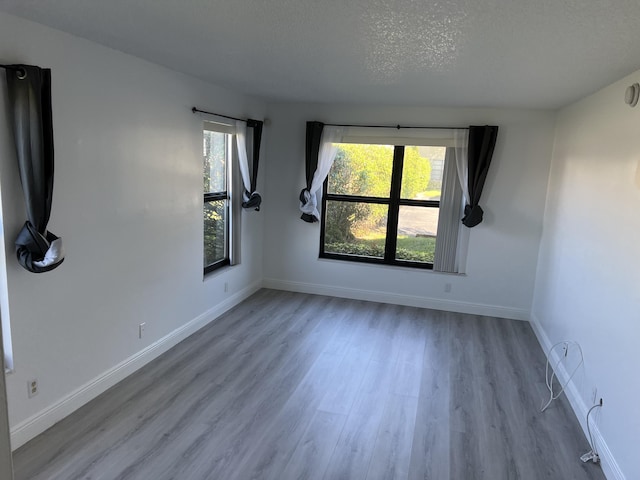 spare room with light hardwood / wood-style floors and a textured ceiling