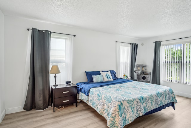 bedroom with light wood-type flooring and a textured ceiling