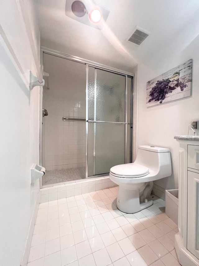 bathroom featuring tile patterned flooring, a shower with door, toilet, and vanity